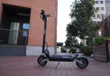 Apollo Phantom electric scooter - full scooter, stem to left, brick ground and building in background